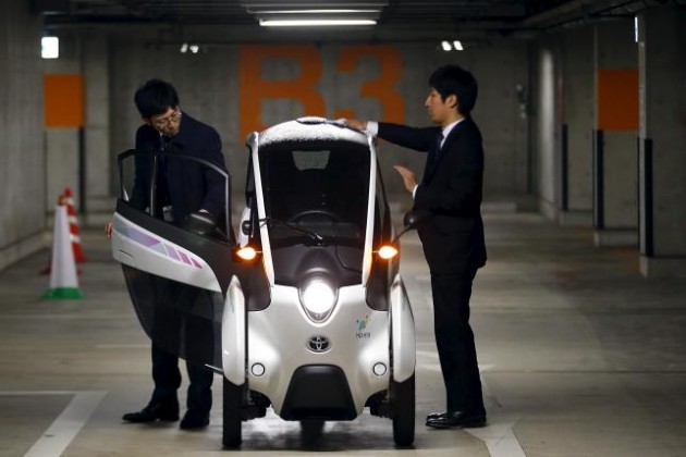Staff members clean Toyota i-Road electric vehicle in Tokyo
