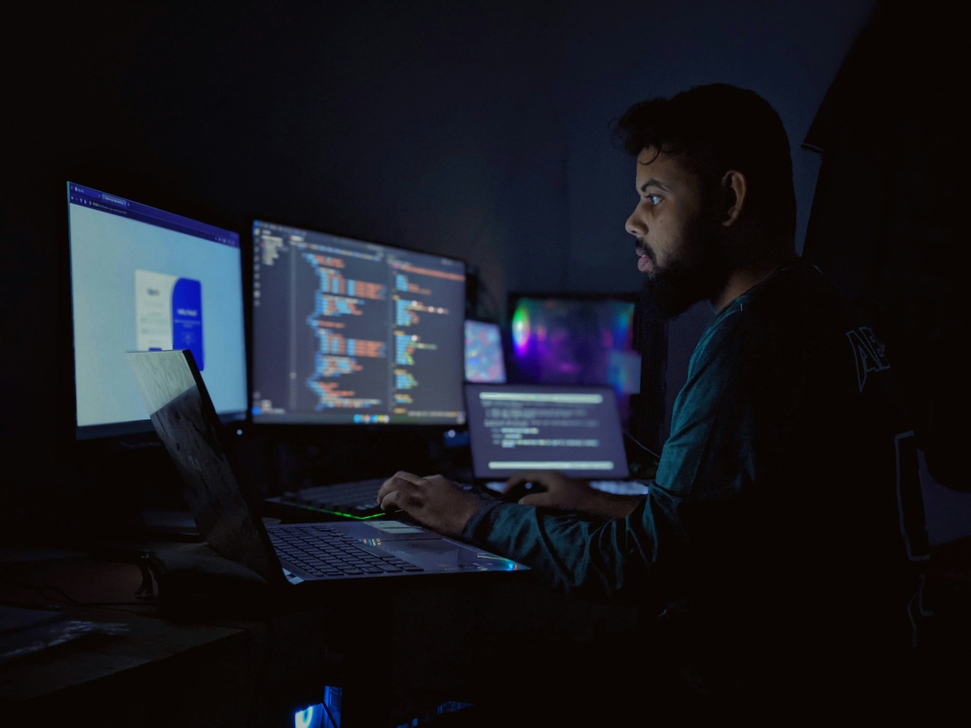 Desarrollador trabajando de noche frente a varias pantallas llenas de código